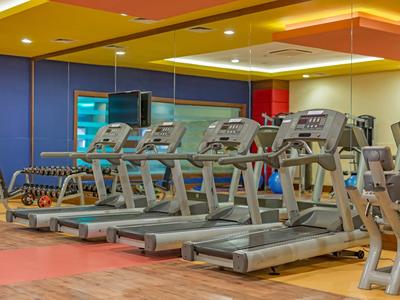 Tapis roulant moderni in una palestra luminosa e colorata dell'hotel.