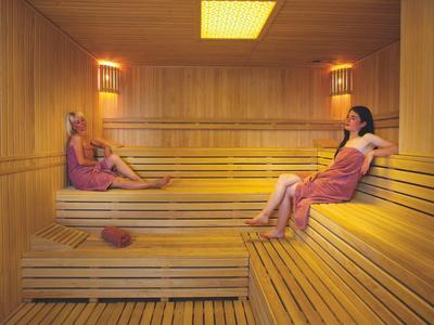 Due donne sedute e rilassate in una sauna di legno.