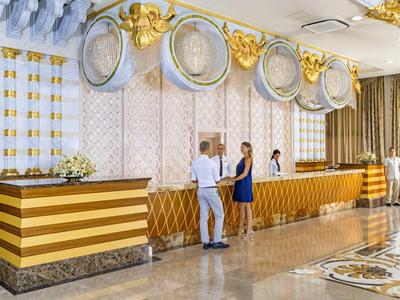 Reception di un hotel elegante con banconi dorati e personale accogliente.