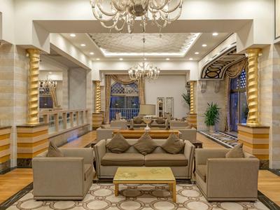 Elegante hall dell'hotel con mobili raffinati e lampadari sotto una luce calda.