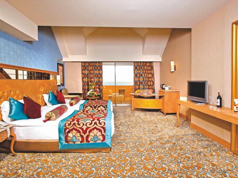 Ampia camera d'albergo con letto matrimoniale, moquette colorata e televisore.