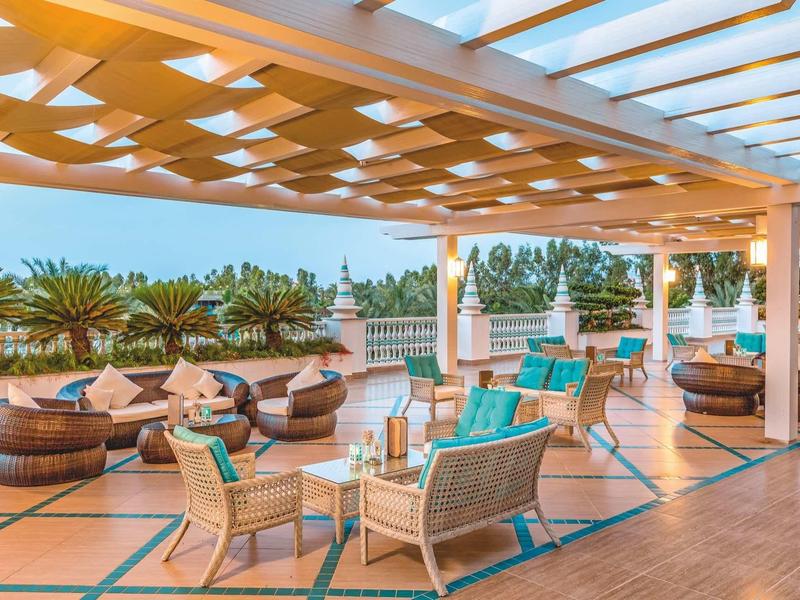 Terrazza con divani all'aperto e vista sulla vegetazione sotto una pergola.