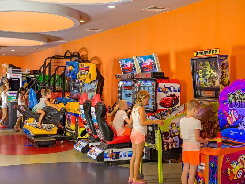 Centro giochi arcade colorato con bambini che giocano ai videogiochi.