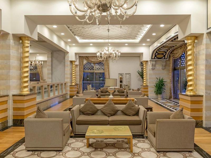 Salotto d'hotel lussuoso con divani, tavolini e lampadari eleganti.