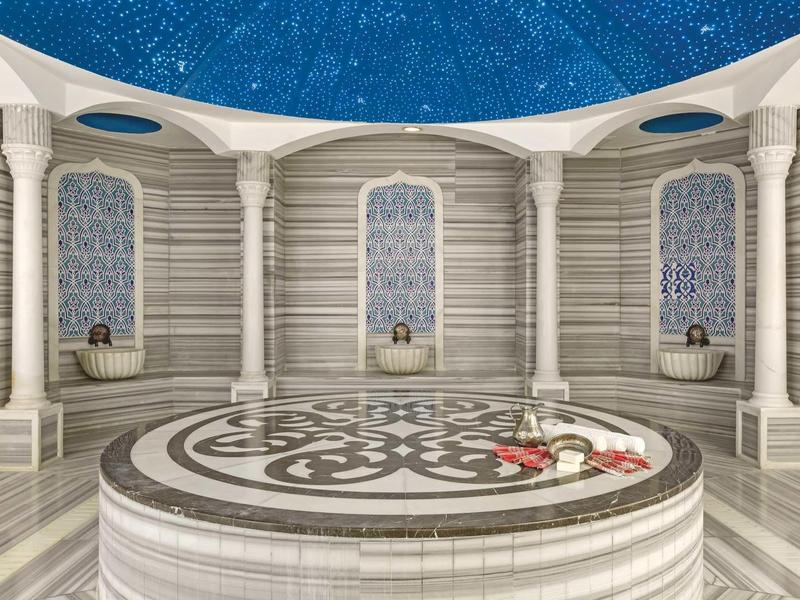 Interno di un bagno turco con marmo bianco e soffitto blu stellato.