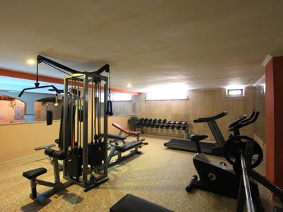 Una palestra con varie attrezzature e manubri, ben illuminata.