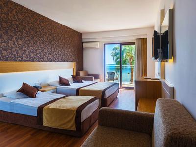 Camera d'hotel moderna con due letti, balcone e vista su palme.