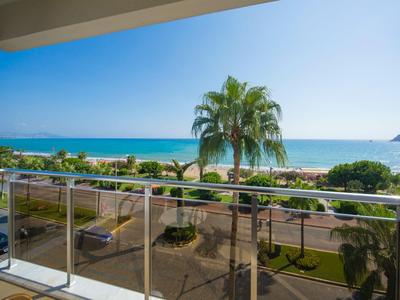 Vista dal balcone su una spiaggia con palme e mare blu sotto un cielo sereno.