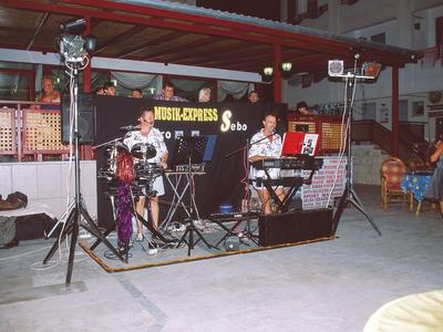 Una piccola band dal vivo che suona su un palco al chiuso davanti a un pubblico.