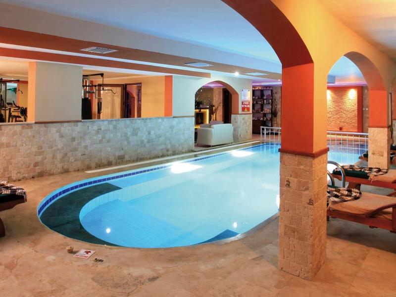 Piscina interna accogliente con lettini e illuminazione calda in una lounge dell'hotel.