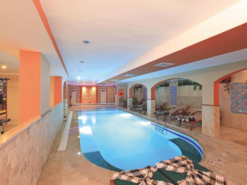 Piscina coperta con lettini e pareti in pietra decorativa in un'area dell'hotel.