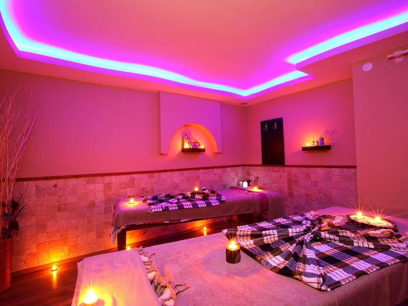 Accogliente sala benessere con illuminazione soffusa e lettini da massaggio.