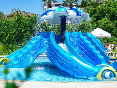 Colorful inflatable water slide play structure in an outdoor pool with green background.
