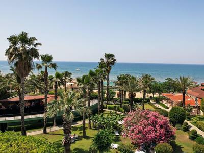 Blick auf einen Garten mit Palmen und bunter Vegetation am Meer mit blauem Himmel