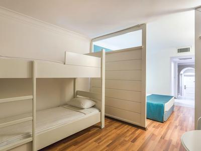 Simple white bunk bed in a room with wooden flooring and partition wall.