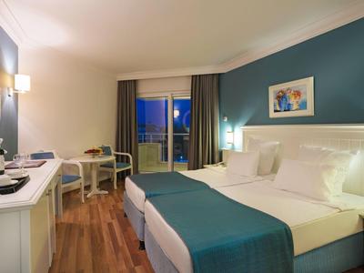 Modern hotel room with double bed, desk, and large window with curtains.