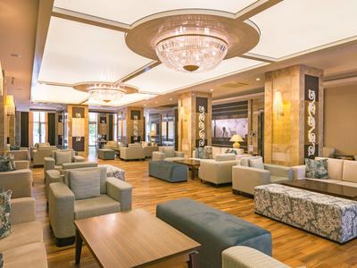 Geräumige Hotellobby mit bequemen Sitzgelegenheiten, warmem Holzfußboden und elegantem Kronleuchter.