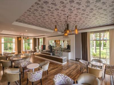 Eleganter Hotel-Loungebereich mit floraler Decke, Holzboden und gemütlichen Sitzgruppen.