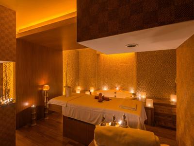 Gemütlicher Massageraum mit warmem Licht, zwei Behandlungsliegen und beruhigender Atmosphäre.