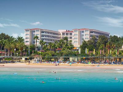 Großes Hotel am Strand mit Palmen und glasklarem blauem Wasser.