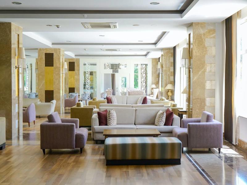 Area lounge dell'hotel luminosa e moderna con divani e poltrone su pavimento in legno.