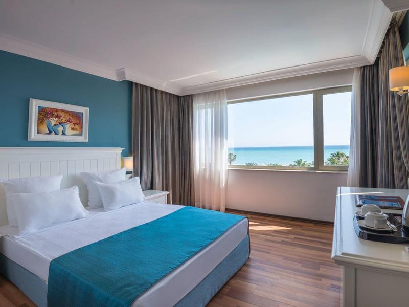 Camera d'hotel moderna con letto grande, vista mare attraverso una grande finestra.