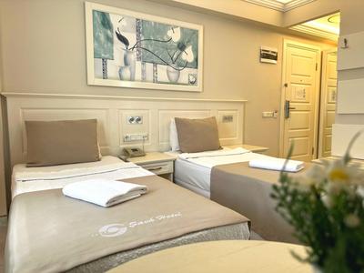 Camera d'hotel con due letti singoli, arredi minimal e un quadro incorniciato sulla parete.