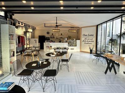 Caffè luminoso con arredamento moderno, tavoli e sedie, grandi finestre e decorazioni murali.