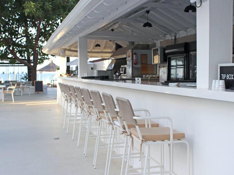 Area bar esterna moderna con sgabelli alti e vista sul mare.