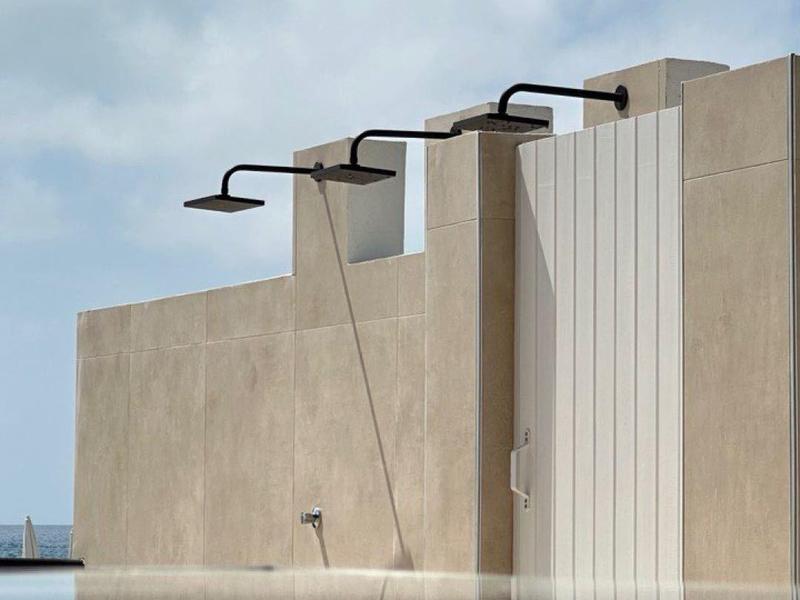 Architettura moderna con lampade esterne e riflesso nell'acqua sotto un cielo sereno.