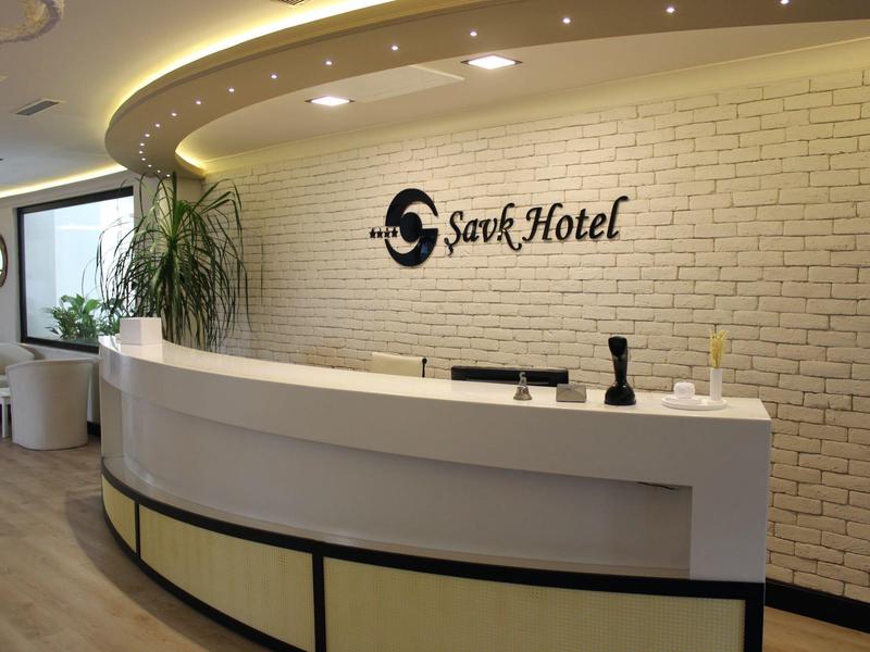 Hall dell'hotel moderno con banco reception curvo e parete di mattoni bianchi.