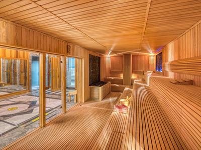 Innenraum einer hölzernen Sauna mit mehrstufigen Bänken und warmem Licht.