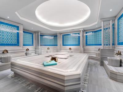 Eleganter türkischer Hamam mit großem Marmor-Tisch und blauen Mosaikfliesen an den Wänden.