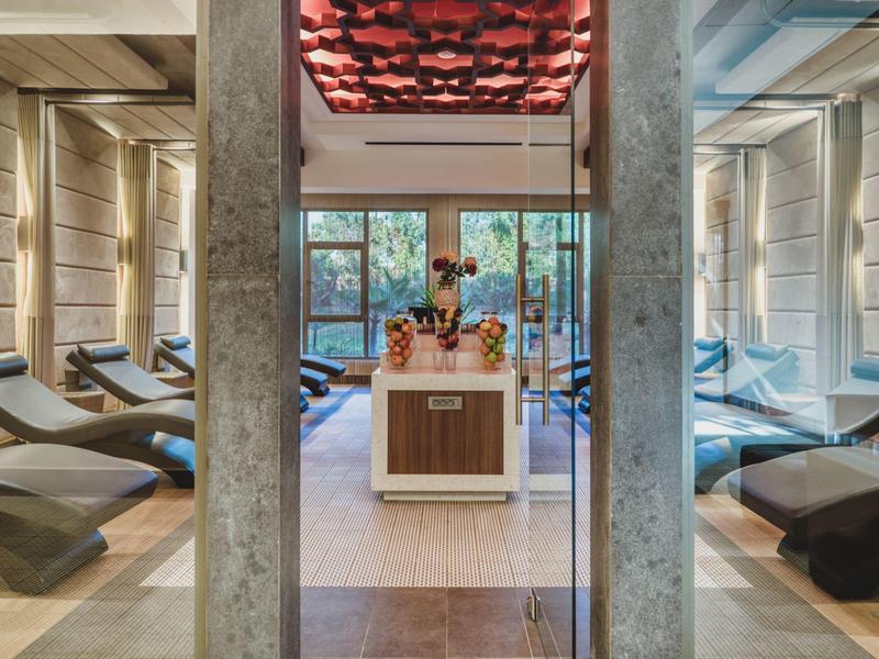 Modern spa area with lounge chairs and a central wooden table with towels and a plant.
