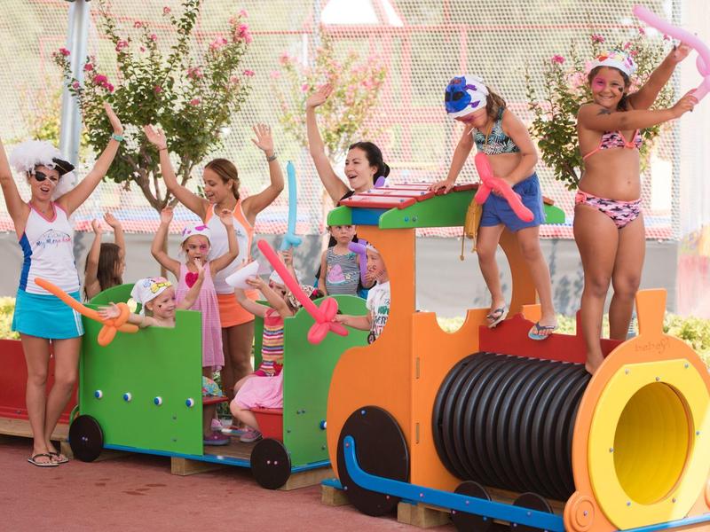 Children and adults playing on a colorful indoor train playground.