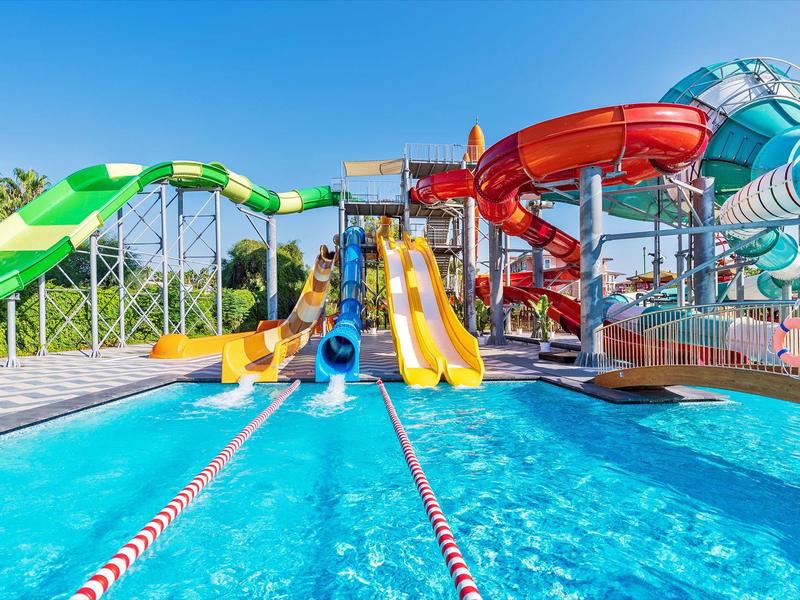 Bright water park with colorful slides and clear blue pool under a sunny sky.