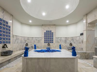 Luxurious bathroom with large bathtub, blue towels, and marble walls.