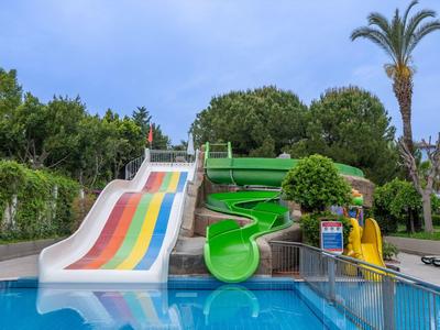 Colorful water slides and pool in a tropical resort surrounded by palm trees and lush greenery.