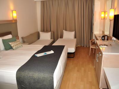 Modern eingerichtetes Hotelzimmer mit zwei Betten, Sitzbereich und Holzboden.