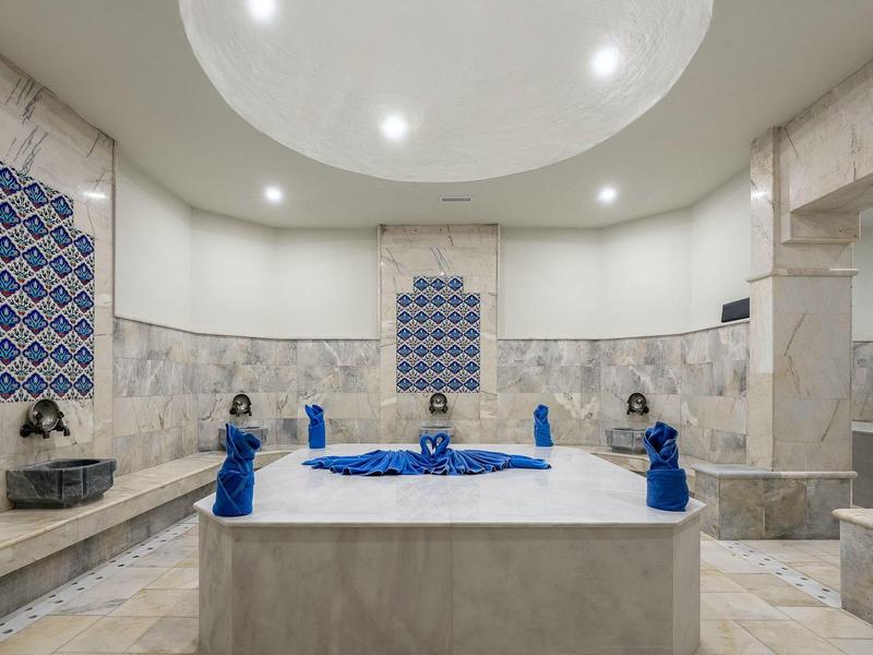 Luxurious bathroom with large bathtub, blue towels, and marble walls.