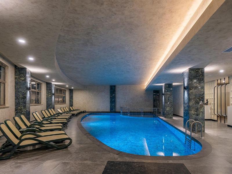 Indoor pool with blue water, surrounded by lounge chairs and modern design.