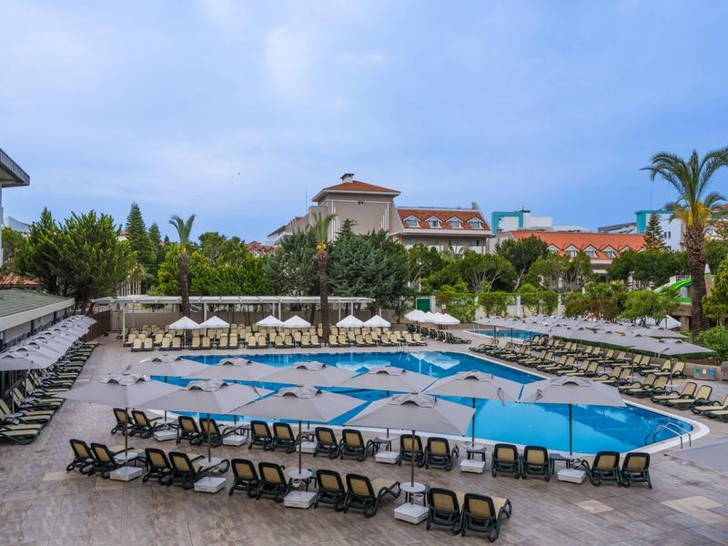 Large hotel pool with lounge chairs and umbrellas in a tropical setting.