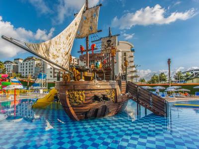 Ein großer hölzerner Piratenschiff-Spielplatz mit Segel, Rutschen und blauem Kachelboden.