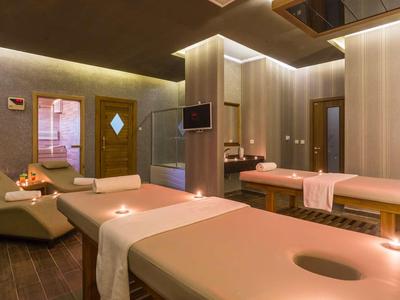 Wellnessraum mit zwei Massageliegen, gedämpftem Licht und entspannender Atmosphäre.