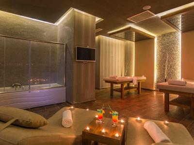 Modernes Spa mit zwei Massageliegen, warmem Licht, dekorativen Pflanzen und entspannter Atmosphäre.