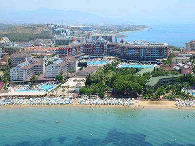 Strand mit Sand, Sonnenschirmen, Hotels und klar blauem Meer im Hintergrund bei bewölktem Himmel.