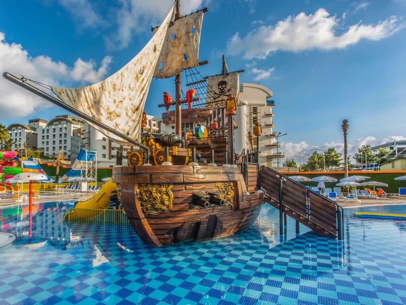 Kinderwasserspielplatz mit einem Piratenschiff und Wasserrutschen unter blauem Himmel.
