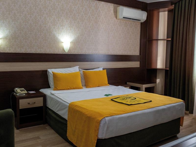 Gemütliches Hotelzimmer mit Doppelbett, gelben Akzenten und moderner Beleuchtung.