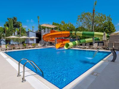Piscine extérieure avec toboggans aquatiques dans un hôtel ensoleillé avec arbres en fleurs.