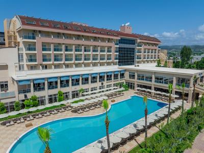 Hôtel moderne avec grande piscine extérieure et chaises longues sous un ciel bleu.